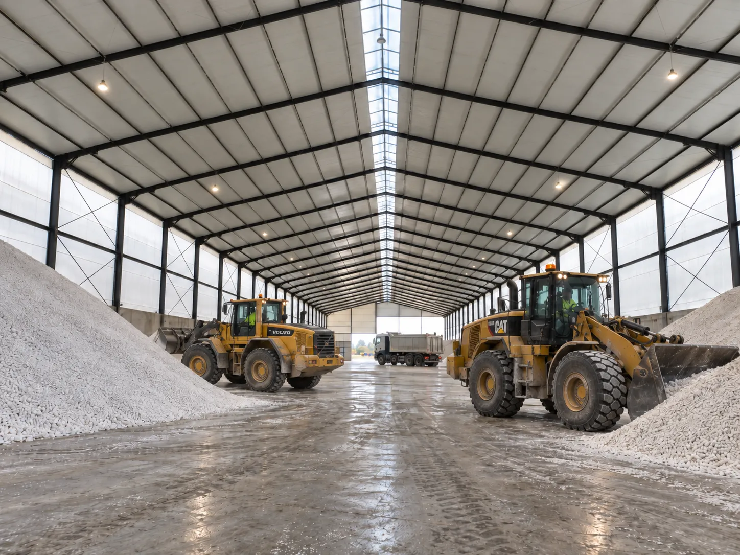 Interior de bodega agroindustrial con fertilizante almacenado a granel y cargadoras frontales en operación